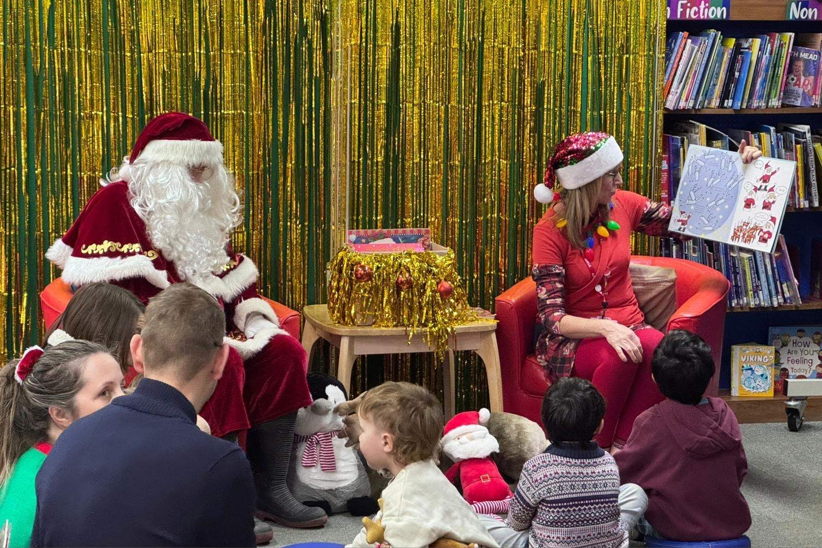 Santa and a St Austell Library staff member reading to children