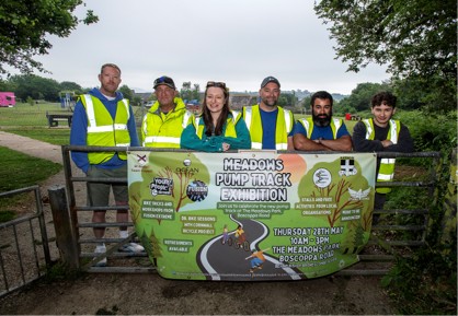 St Austell Town Council staff pose in front of a banner advertising the Meadows Pump Track Exhibition