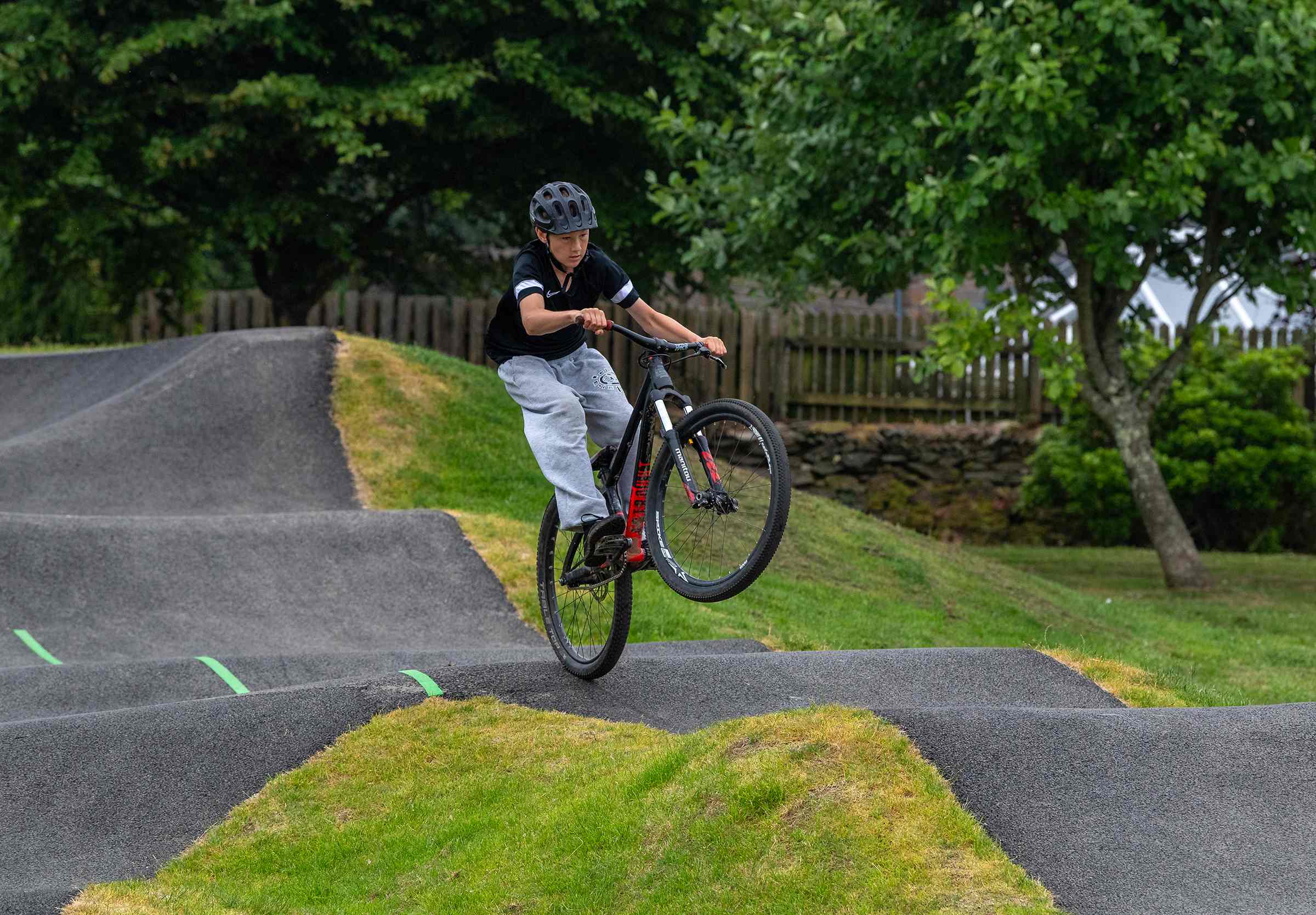 A young man rides a bike in the bowl part of the pump track